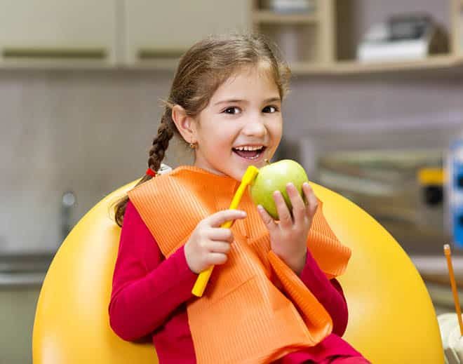 Little Girl Holding an Apple — Your Holistic Dentists in Casuarina, NSW